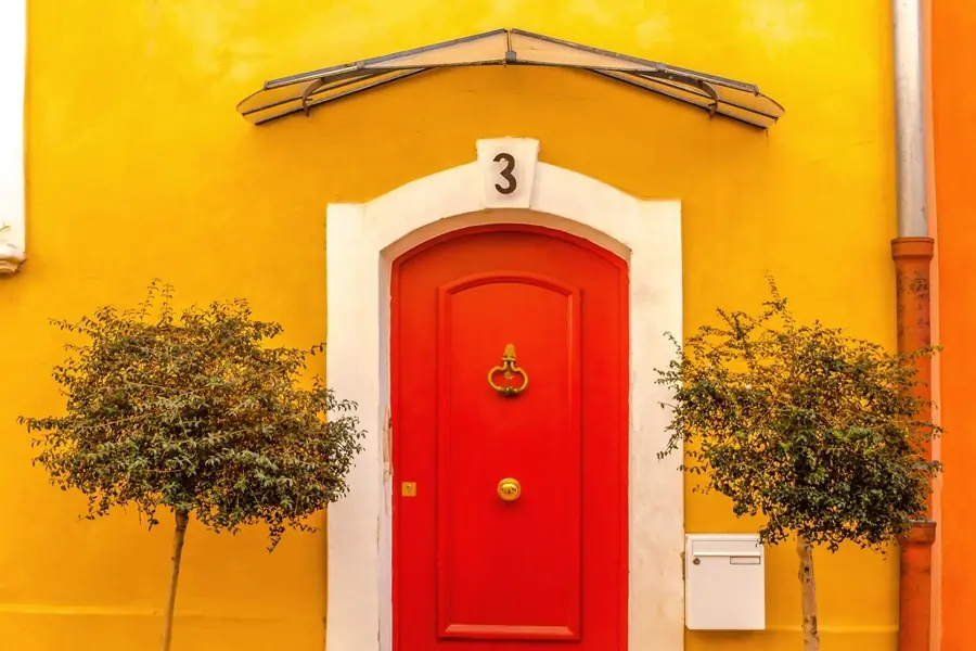 Painted house front with a red front door